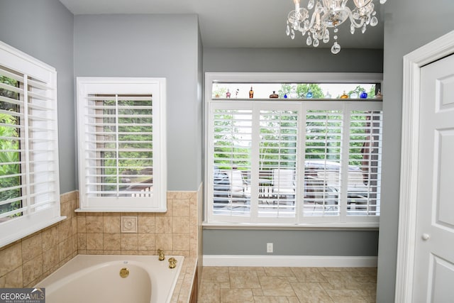 bathroom featuring tiled bath and a chandelier