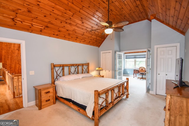 bedroom with high vaulted ceiling, two closets, light colored carpet, and wooden ceiling