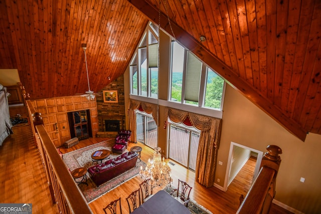 living room featuring wood-type flooring, high vaulted ceiling, wooden ceiling, ceiling fan, and a fireplace