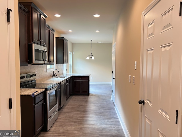 kitchen with stainless steel appliances, hardwood / wood-style floors, sink, pendant lighting, and backsplash