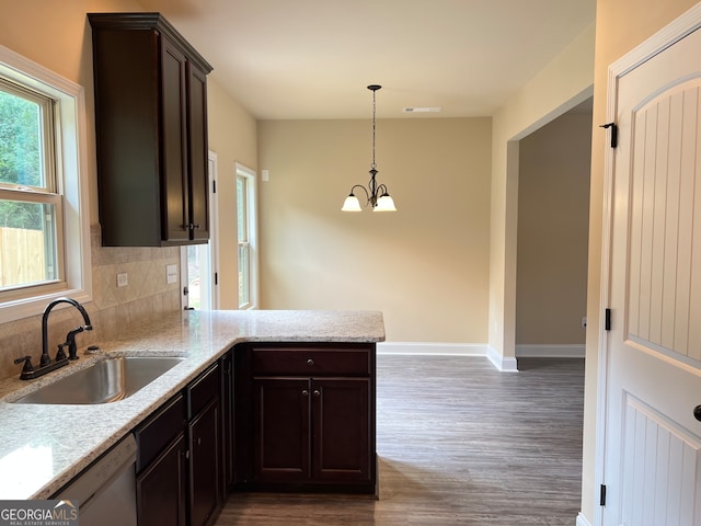 kitchen featuring sink, kitchen peninsula, decorative light fixtures, decorative backsplash, and wood-type flooring