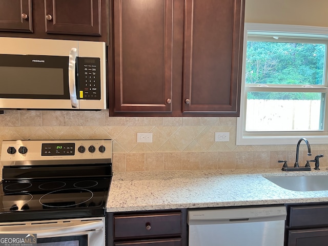 kitchen featuring sink, light stone counters, backsplash, and stainless steel appliances