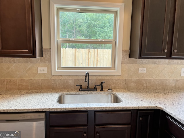 kitchen with a sink, light stone countertops, dark brown cabinetry, and dishwasher