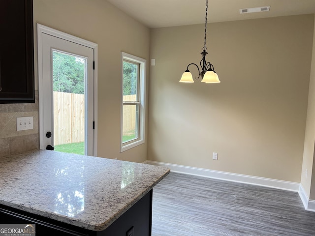 kitchen with baseboards, light stone countertops, visible vents, and pendant lighting