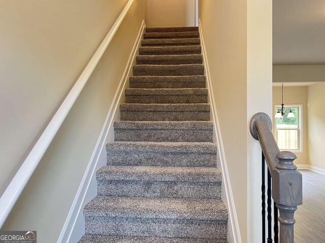 stairs with carpet flooring and a chandelier