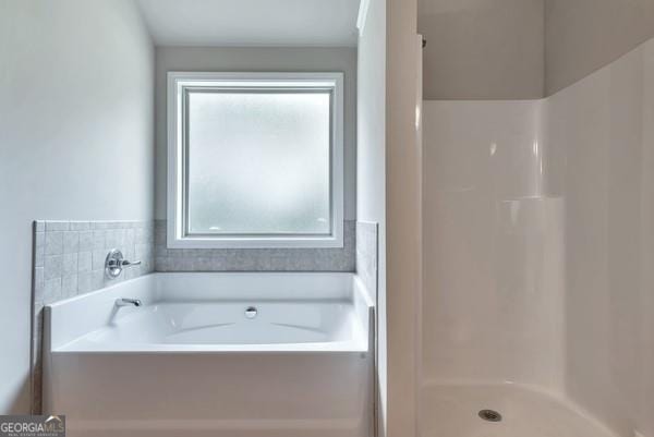 bathroom featuring a stall shower, a bath, and a healthy amount of sunlight