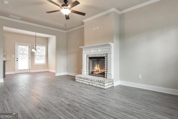 unfurnished living room with dark hardwood / wood-style flooring, a brick fireplace, ceiling fan, and crown molding