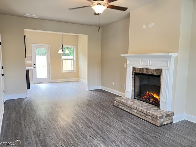 unfurnished living room with dark wood-style floors, a fireplace, baseboards, and ceiling fan