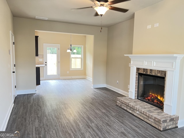 unfurnished living room with a ceiling fan, a brick fireplace, baseboards, and dark wood-style flooring