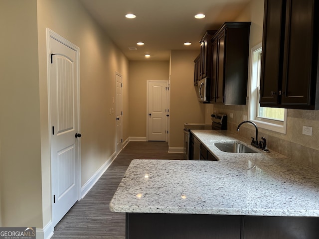 kitchen with light stone counters, a sink, baseboards, appliances with stainless steel finishes, and tasteful backsplash