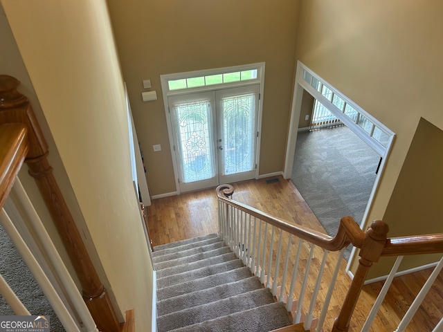 staircase featuring carpet flooring, french doors, and a towering ceiling