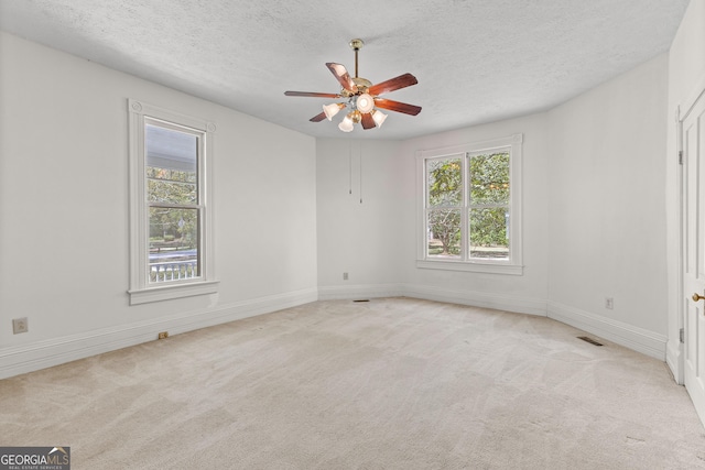 unfurnished room featuring a textured ceiling, light colored carpet, and ceiling fan