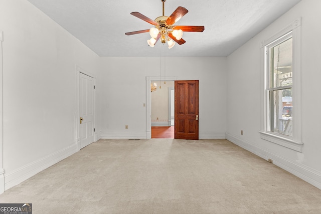 carpeted empty room with ceiling fan with notable chandelier