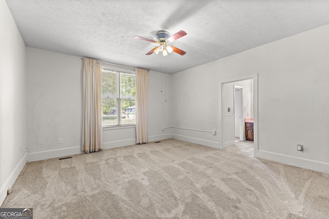 empty room featuring a textured ceiling, ceiling fan, and light carpet