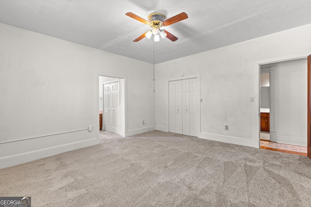 unfurnished bedroom featuring ceiling fan, light colored carpet, and a textured ceiling