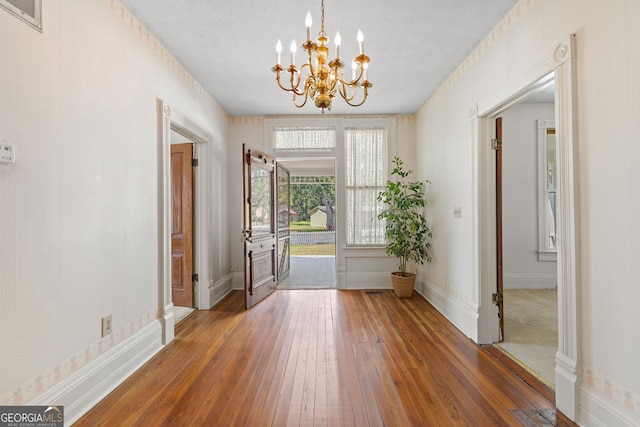 doorway featuring an inviting chandelier, a textured ceiling, and dark hardwood / wood-style floors