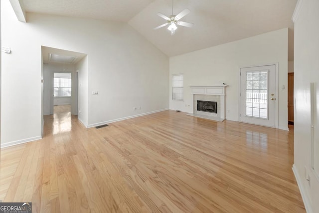 unfurnished living room featuring ceiling fan, high vaulted ceiling, a high end fireplace, and light hardwood / wood-style flooring