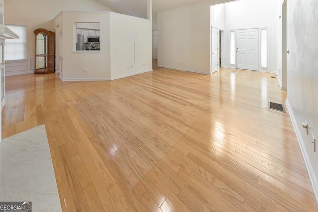 unfurnished living room with high vaulted ceiling and light wood-type flooring