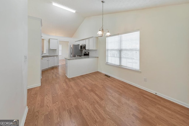 kitchen with appliances with stainless steel finishes, white cabinetry, light hardwood / wood-style floors, vaulted ceiling, and kitchen peninsula