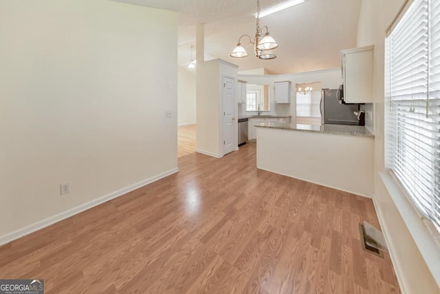 kitchen featuring appliances with stainless steel finishes, white cabinetry, a notable chandelier, decorative light fixtures, and light wood-type flooring