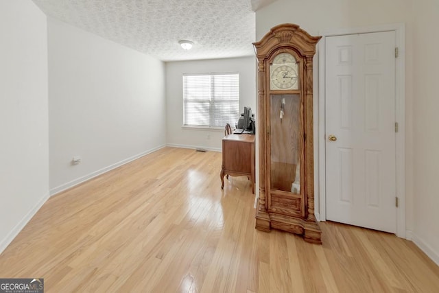 office area with a textured ceiling and light hardwood / wood-style floors