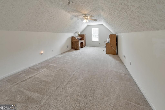 additional living space featuring vaulted ceiling, light carpet, ceiling fan, and a textured ceiling