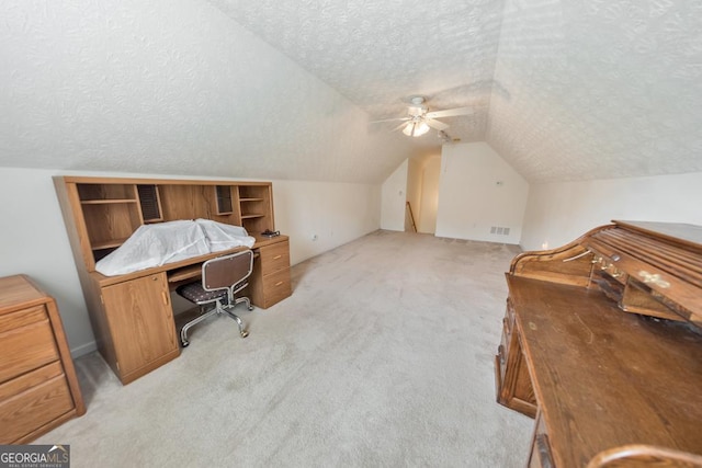 carpeted office space featuring ceiling fan, vaulted ceiling, and a textured ceiling