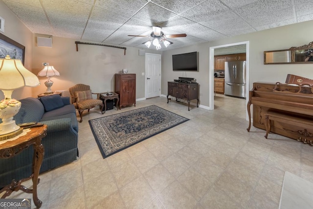 living room with a drop ceiling and ceiling fan