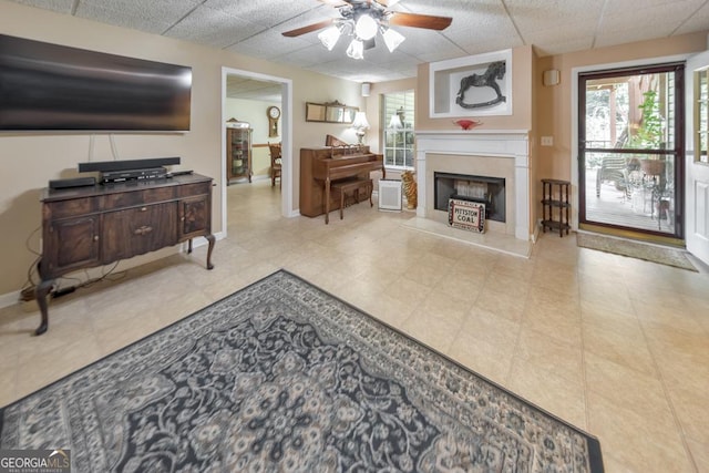 living room featuring a healthy amount of sunlight, a drop ceiling, and ceiling fan