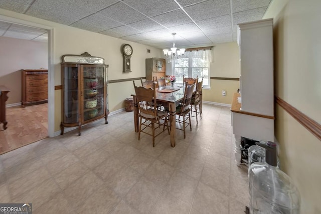 dining space featuring a drop ceiling and an inviting chandelier