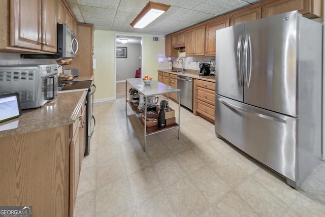 kitchen with appliances with stainless steel finishes, sink, and a paneled ceiling