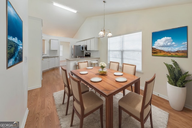 dining area featuring vaulted ceiling, light hardwood / wood-style flooring, and a notable chandelier