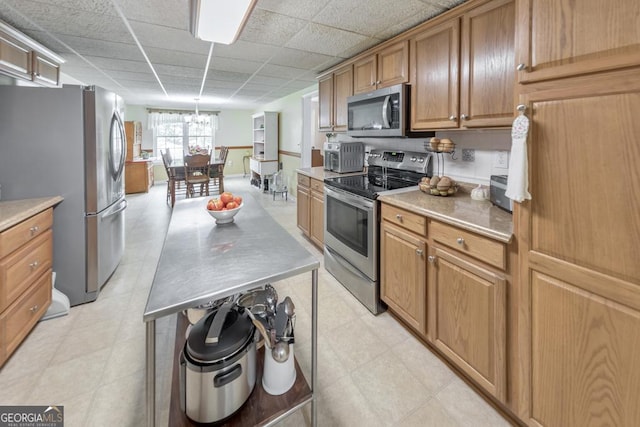 kitchen featuring a drop ceiling, stainless steel appliances, a center island, and a chandelier