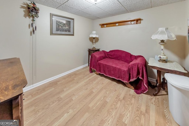 living area with a drop ceiling and light hardwood / wood-style floors