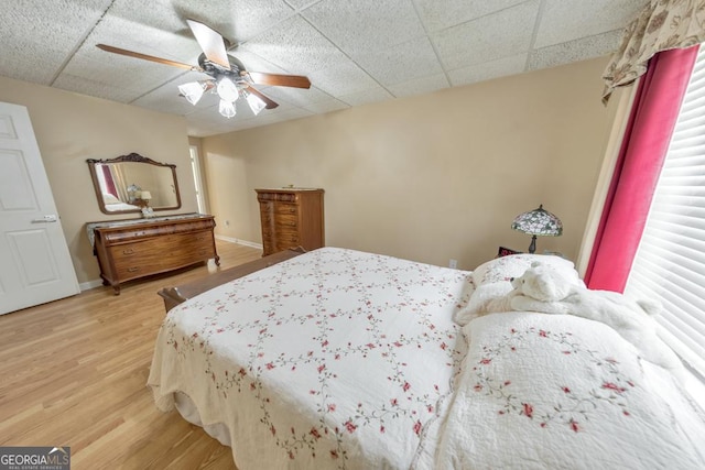 bedroom featuring hardwood / wood-style flooring, ceiling fan, and a drop ceiling