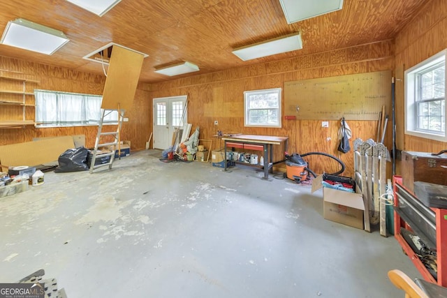 miscellaneous room with concrete flooring, a wealth of natural light, wood ceiling, and wooden walls