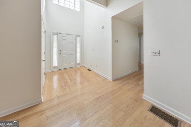 foyer entrance featuring light hardwood / wood-style floors and a high ceiling