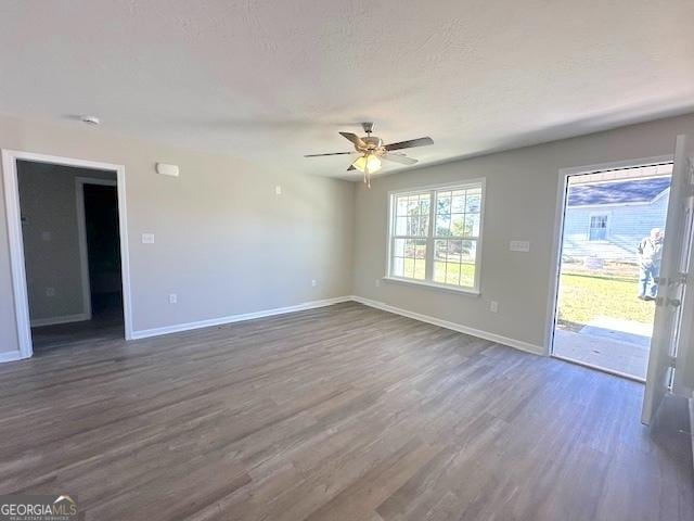 unfurnished living room with a textured ceiling, dark wood-type flooring, and ceiling fan