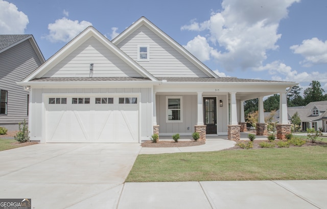 view of front of home with a garage, a porch, and a front yard