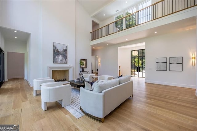 living room with a towering ceiling and light hardwood / wood-style flooring