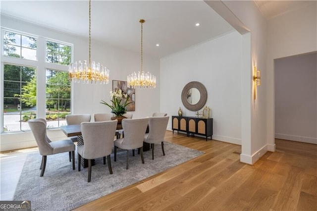 dining room with wood-type flooring, a healthy amount of sunlight, and a notable chandelier