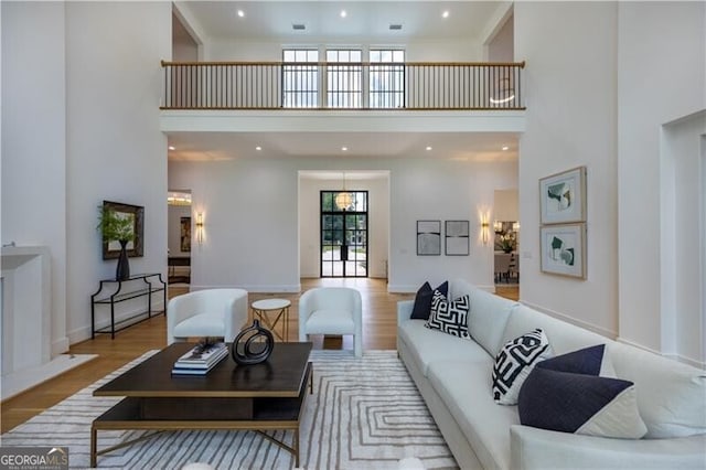 living room with a towering ceiling, french doors, and light hardwood / wood-style flooring