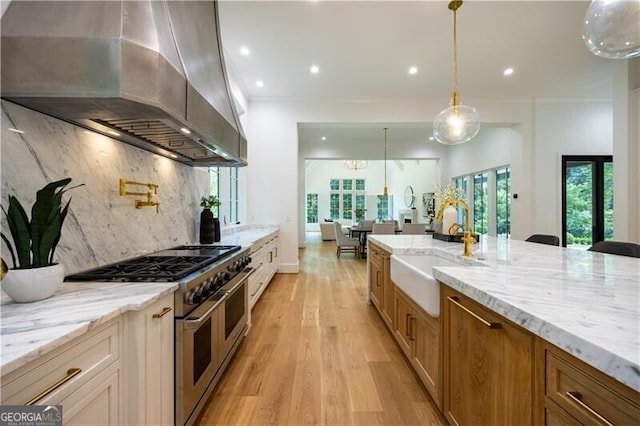 kitchen featuring range hood, light stone countertops, range with two ovens, pendant lighting, and decorative backsplash