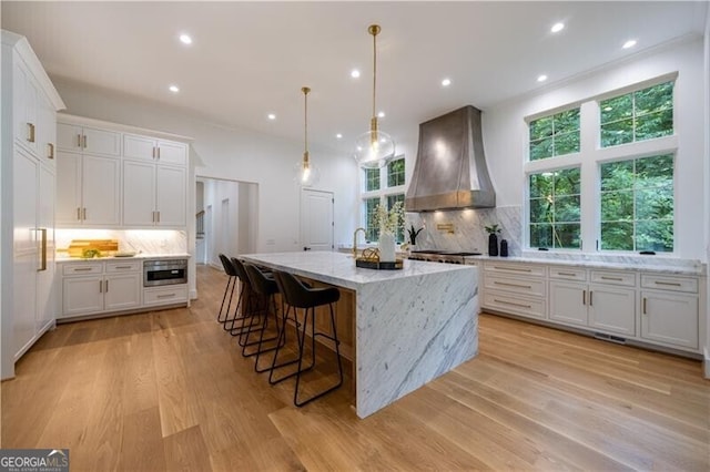 kitchen with white cabinets, backsplash, and premium range hood