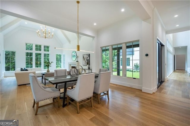 dining space featuring high vaulted ceiling, a chandelier, and light hardwood / wood-style flooring