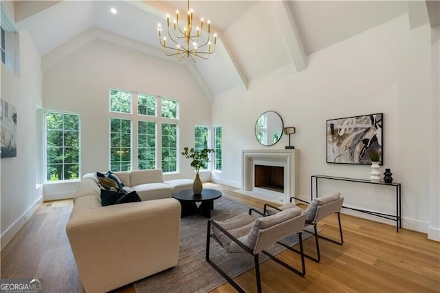 living room featuring high vaulted ceiling, an inviting chandelier, and light hardwood / wood-style floors