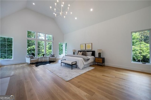 bedroom featuring high vaulted ceiling, an inviting chandelier, and light hardwood / wood-style floors