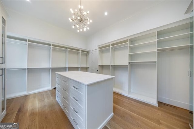 walk in closet featuring an inviting chandelier and light hardwood / wood-style flooring