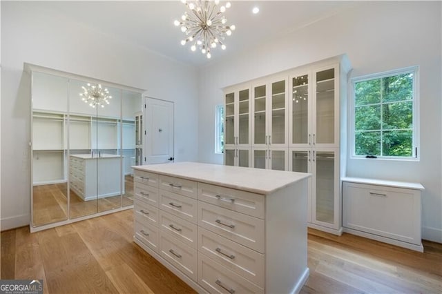 walk in closet featuring light hardwood / wood-style floors and a chandelier