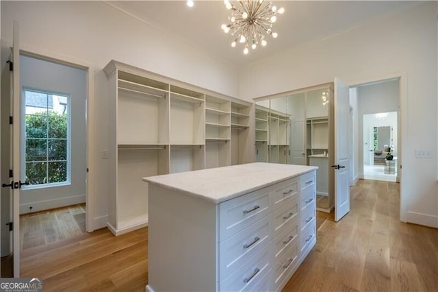 walk in closet with a notable chandelier and light hardwood / wood-style flooring